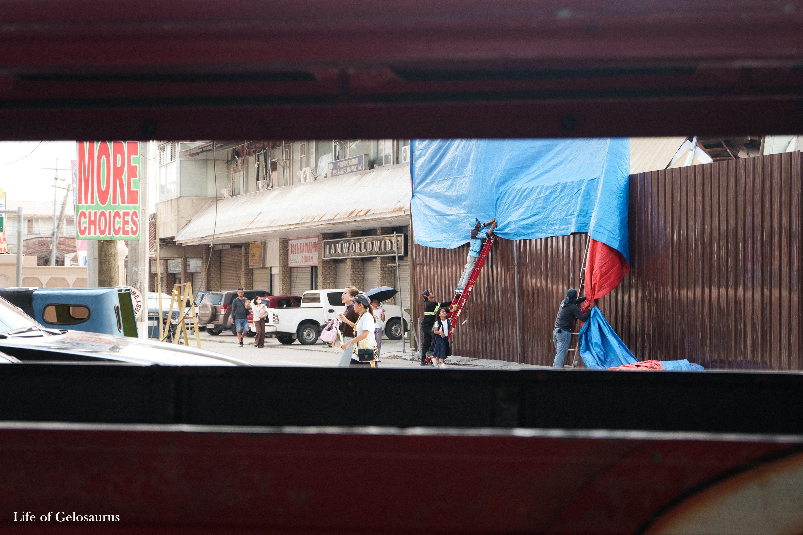 People working with a blue tarp along a street in General Santos City.