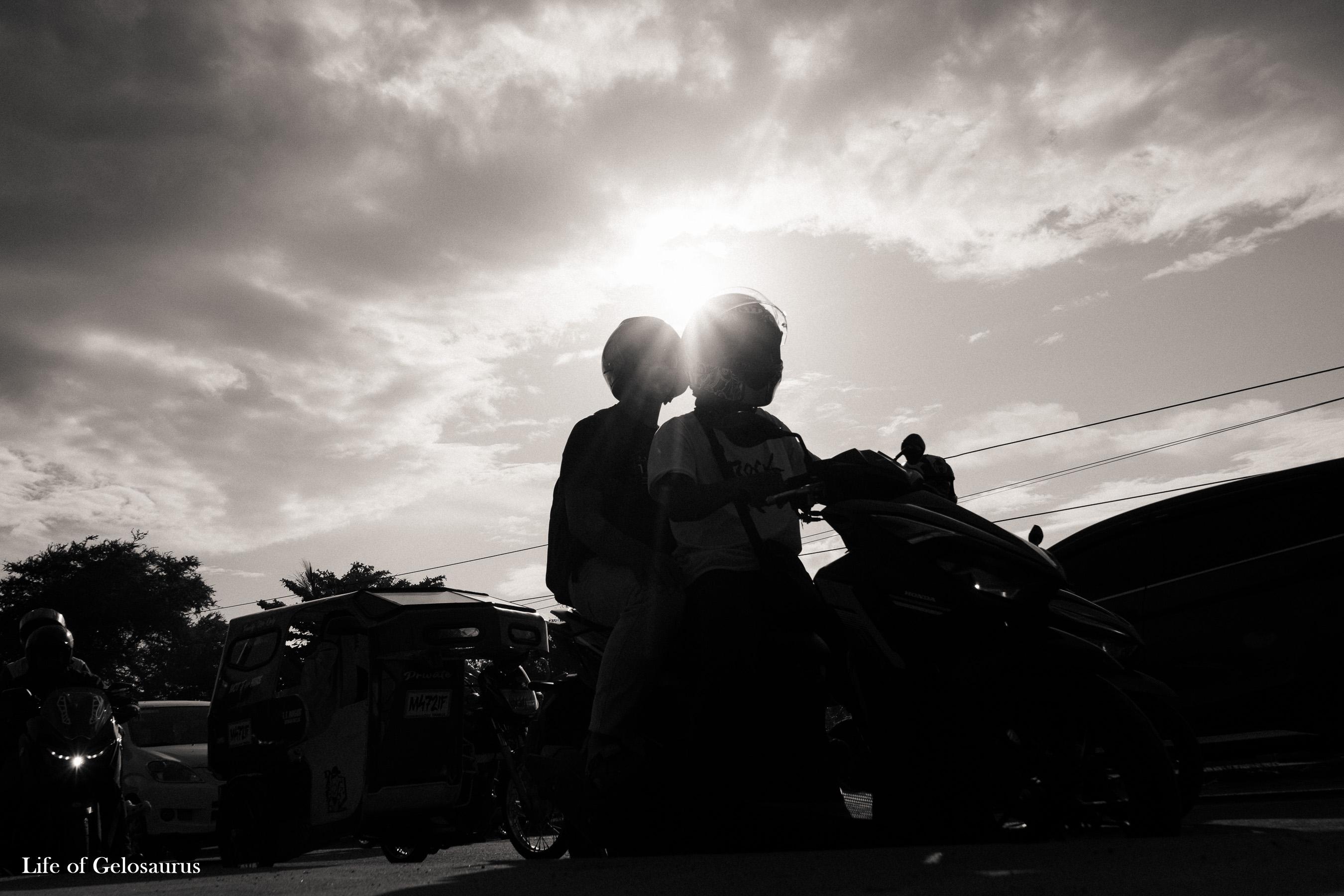 Two helmeted riders silhouetted against the sun on a motorcycle in General Santos City.