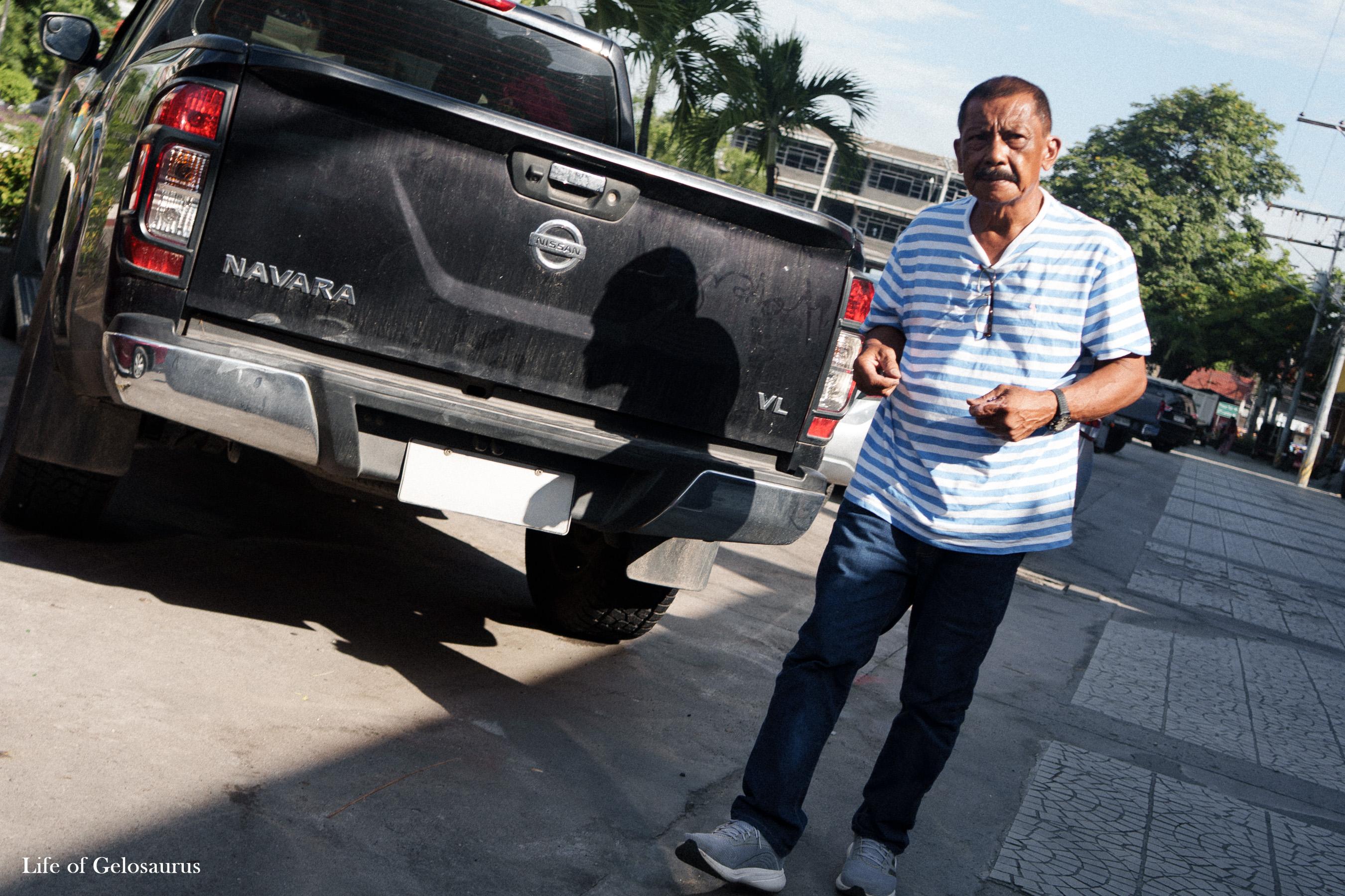 A man standing beside a black pickup truck on a street in General Santos City.