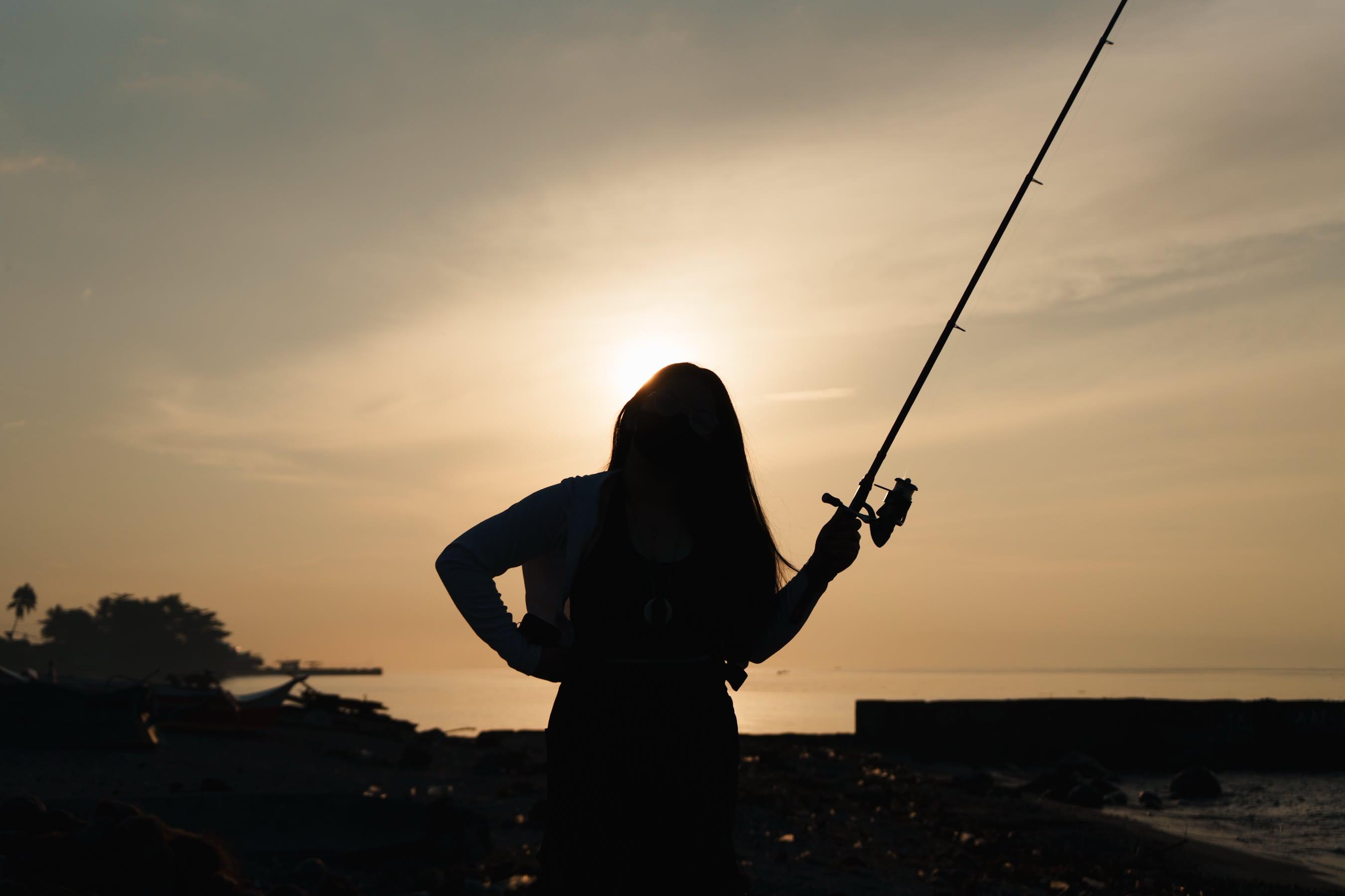 A photographer standing by the water at sunset